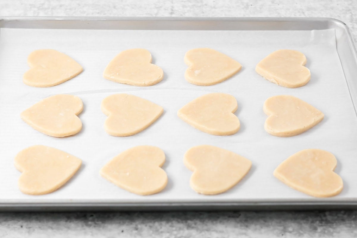 Cut out flaky pie crust dough hearts on baking sheet.