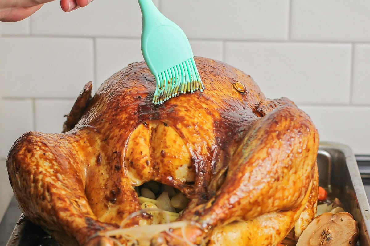 Roast turkey with glaze in roasting pan.