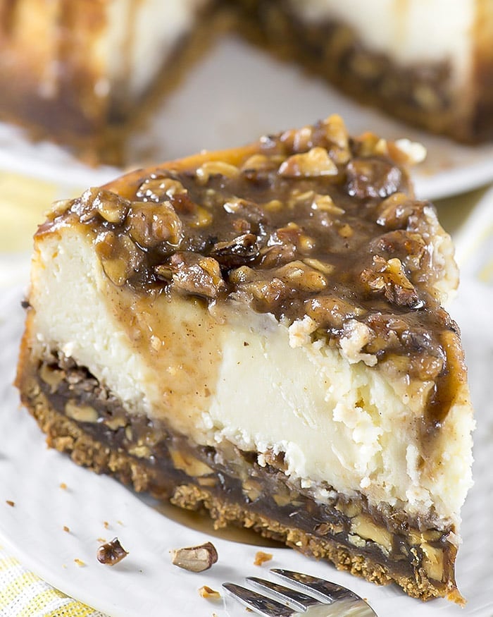 Slice of pecan pie cheesecake with all layers visible.