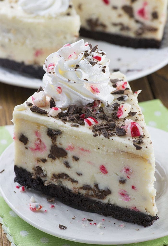 Peppermint Bark Cheesecake - It has three delicious layer-Oreo crust, creamy cheesecake filling loaded with peppermint bark pieces and white chocolate ganache on top garnished with crushed candy canes, whipped cream and chocolate.