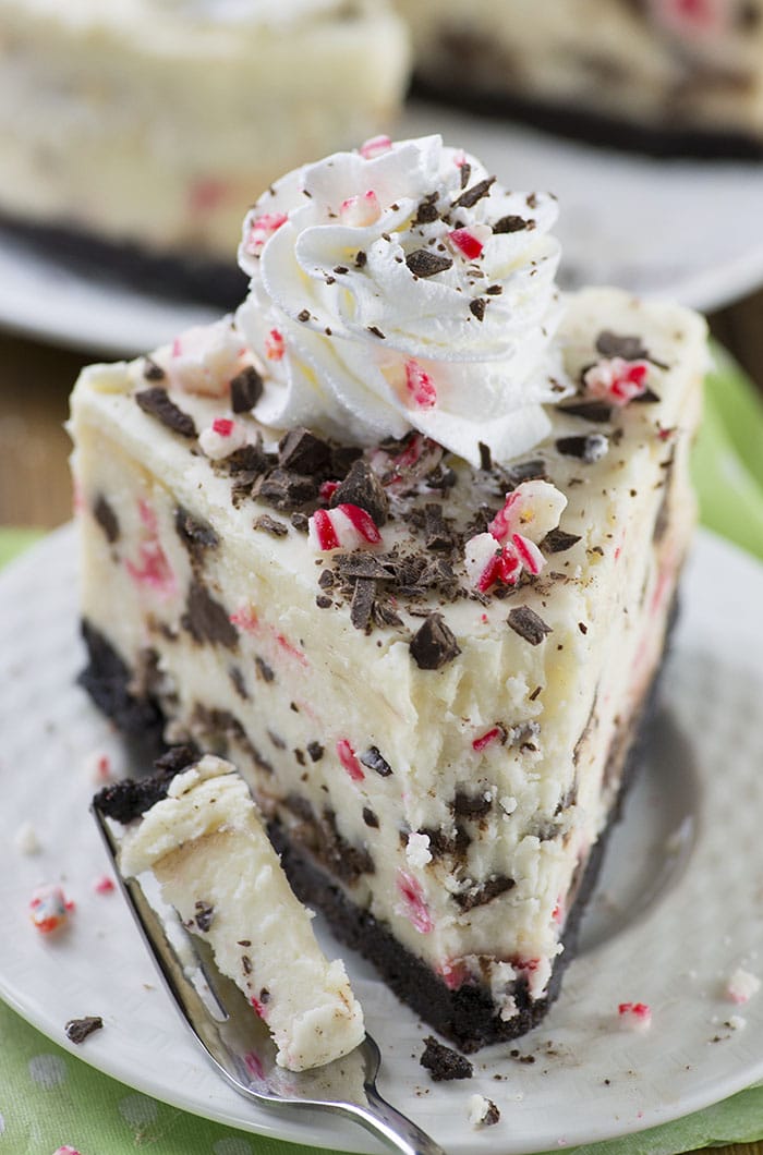 Peppermint Bark Cheesecake - It has three delicious layer-Oreo crust, creamy cheesecake filling loaded with peppermint bark pieces and white chocolate ganache on top garnished with crushed candy canes, whipped cream and chocolate.