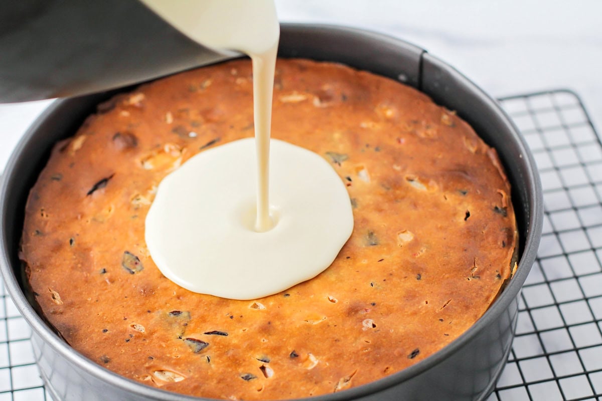 White chocolate ganache being poured over cheesecake.