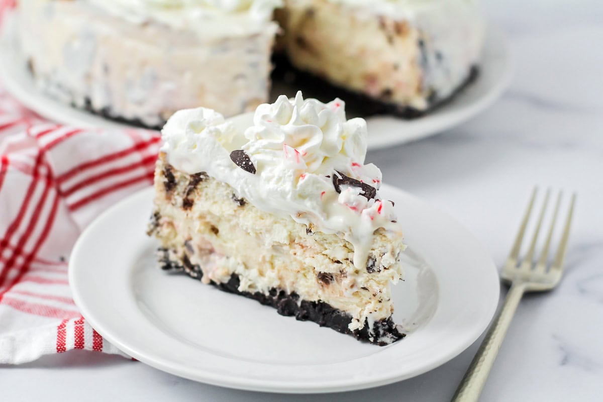 A slice of peppermint cheesecake on white plate with fork.