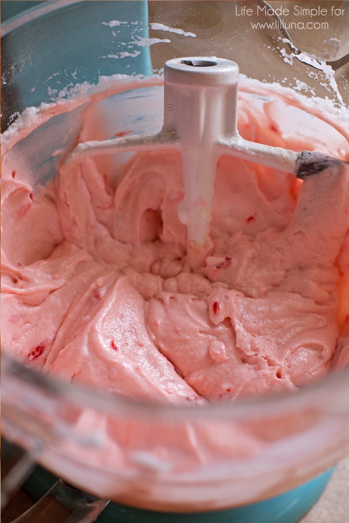Pink cupcake batter in a glass mixing bowl.
