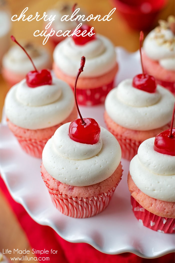 kirsebær mandel cupcakes med et kirsebær på toppen, vises på en hvit plate.