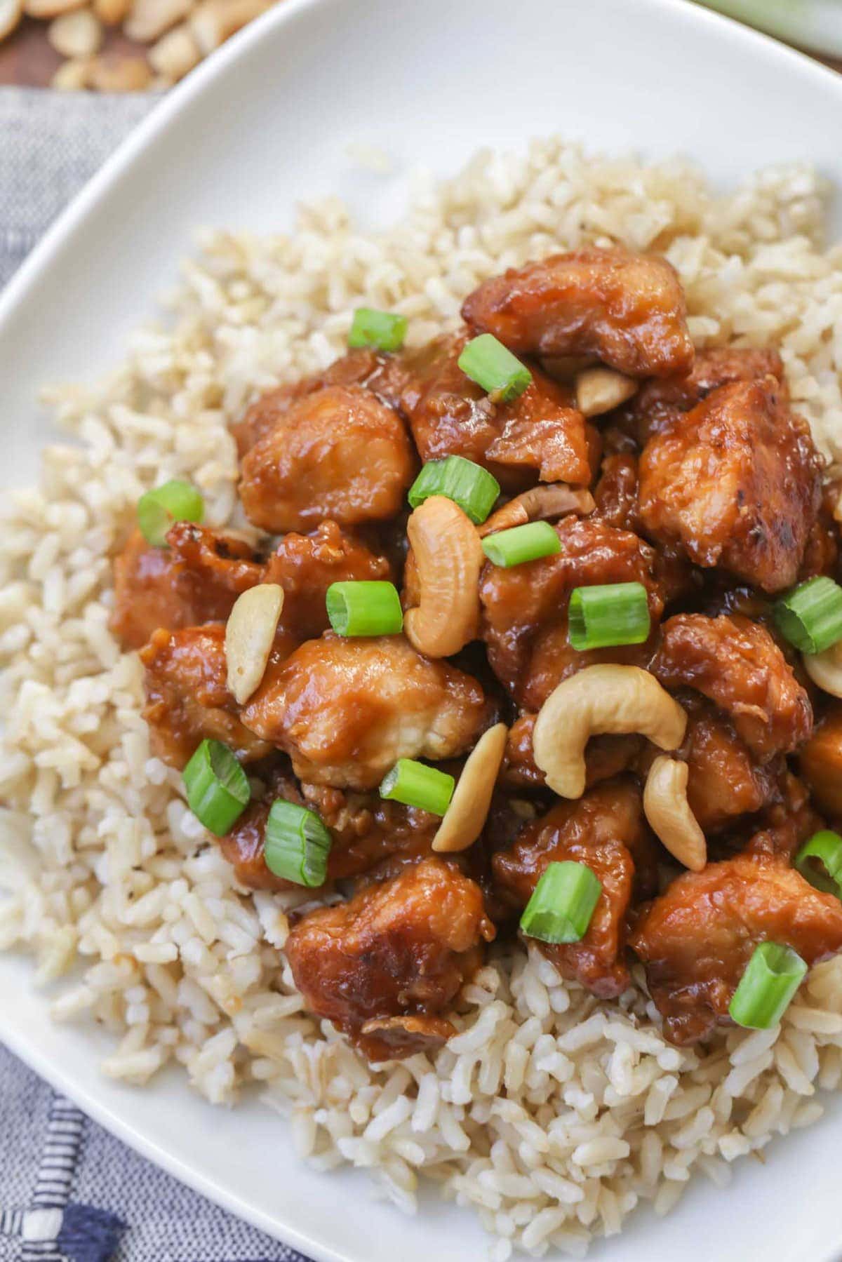 Slow Cooker Cashew Chicken served over brown rice on white plate