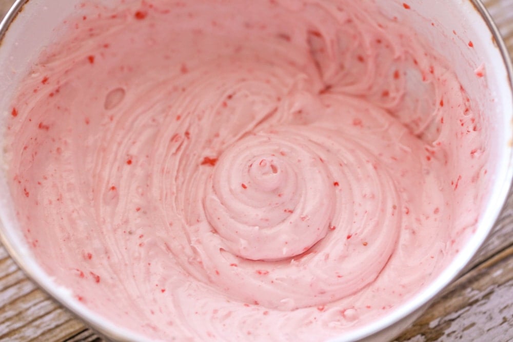Strawberry frosting in a bowl for topping strawberry sheet cake.