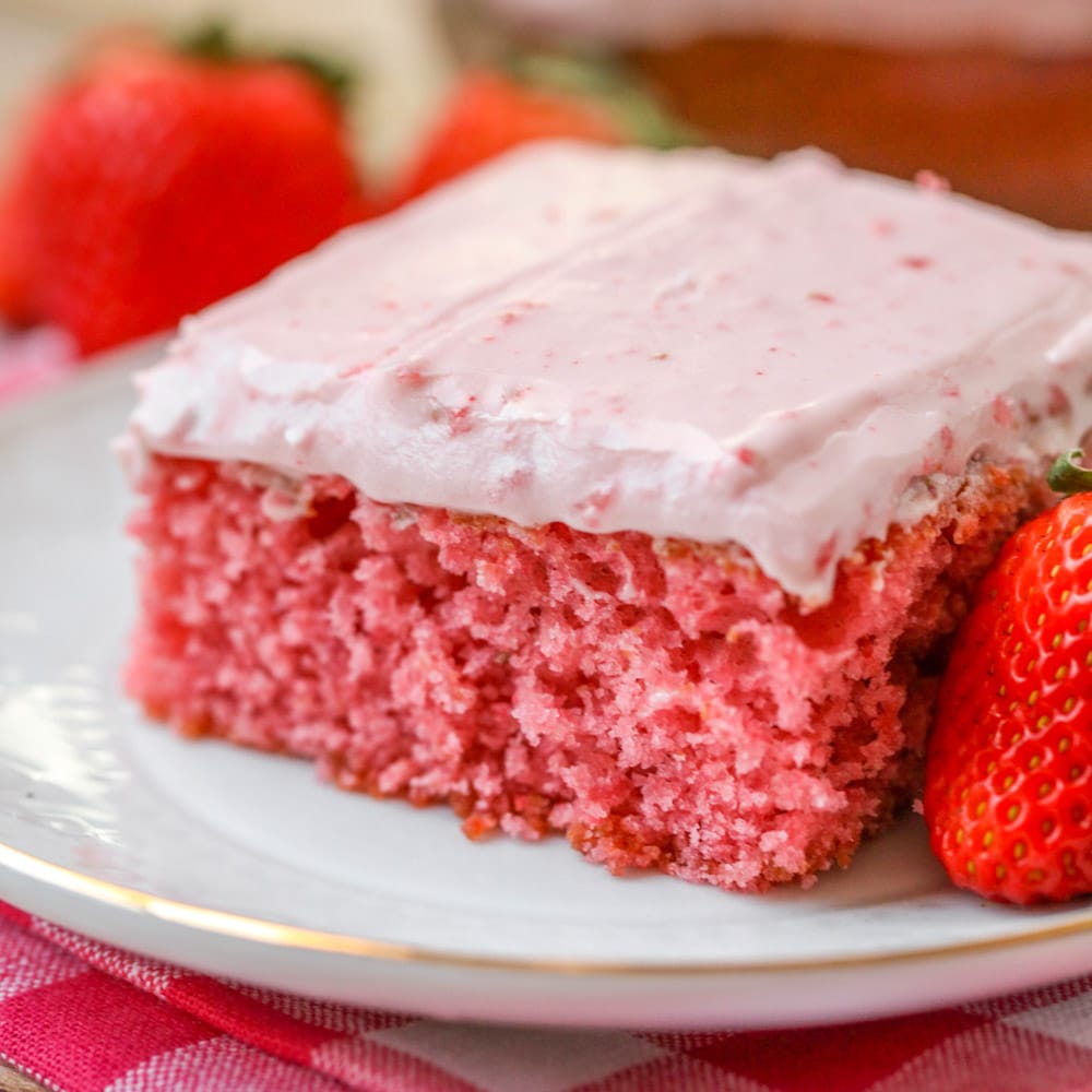 Fresh strawberry sheet cake sliced and served on a white plate.