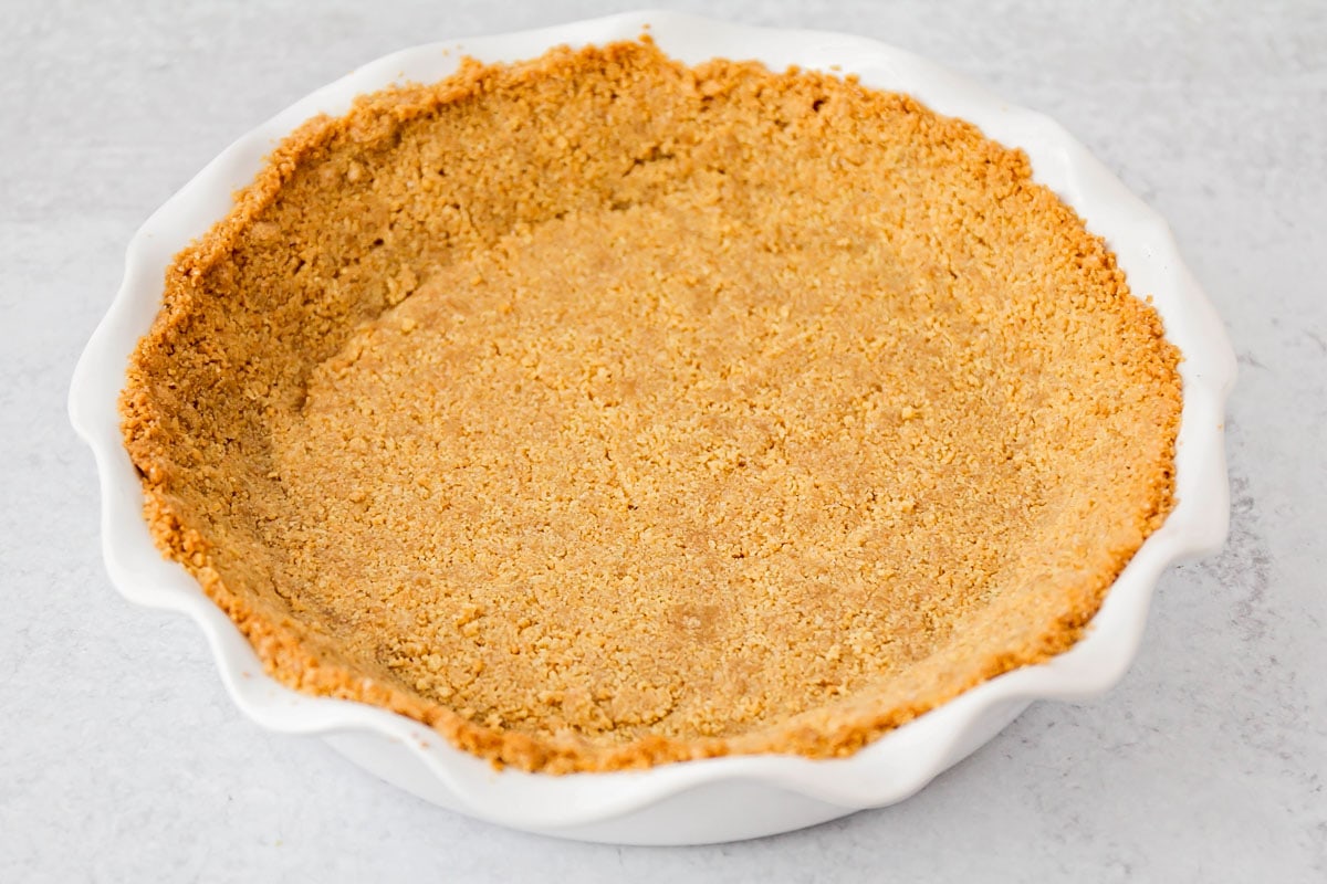 Crust for banana pudding cheesecake in a white pie pan. 