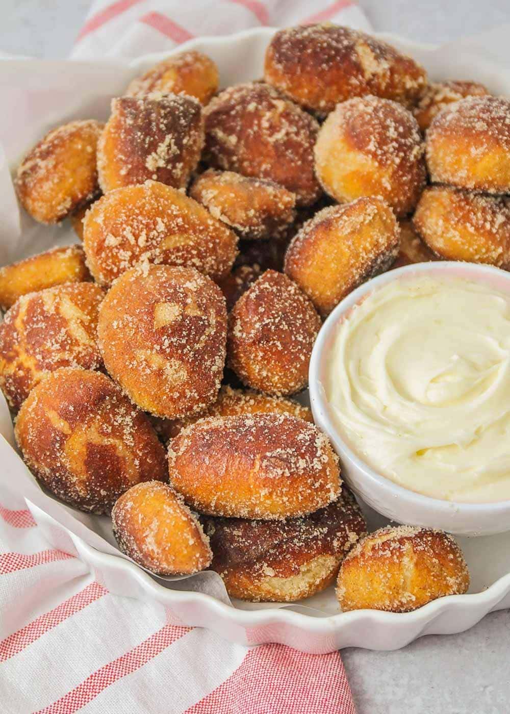 Auntie Anne's cinnamon sugar pretzel bites on a platter with a side of cream cheese dip