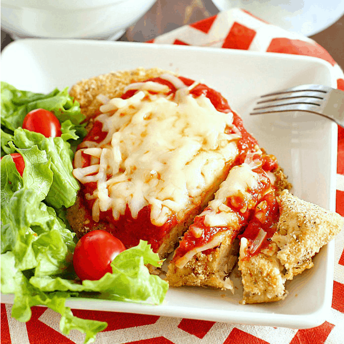 Healthy Chicken Parmesan on plate served with salad