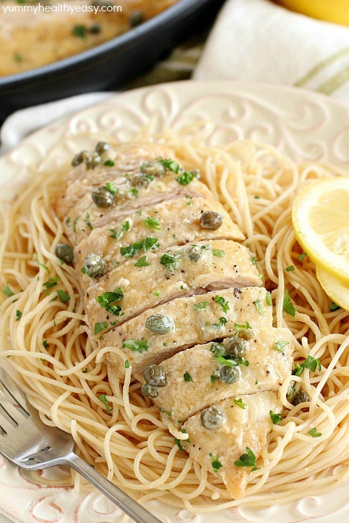  Healthy Dinner Ideas - Healthy Chicken Piccata sliced and served on top of spaghetti garnished with lemon slices.