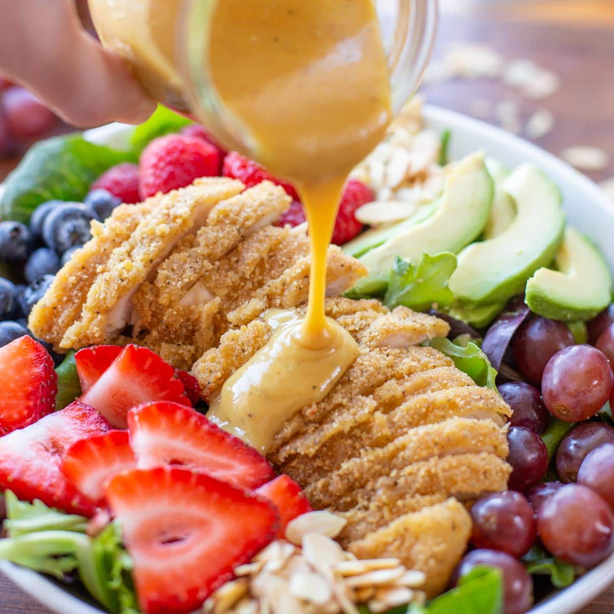 Pouring dressing over honey mustard chicken salad