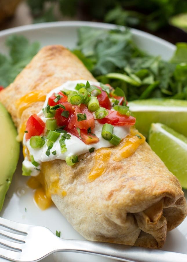 Chicken Dinner Ideas - Baked chicken chimichangas topped with sour cream and fresh tomatoes and green onions.