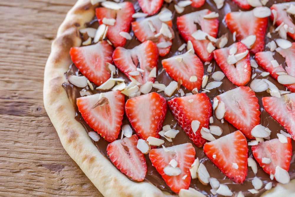 Strawberries layered on a nutella pizza.
