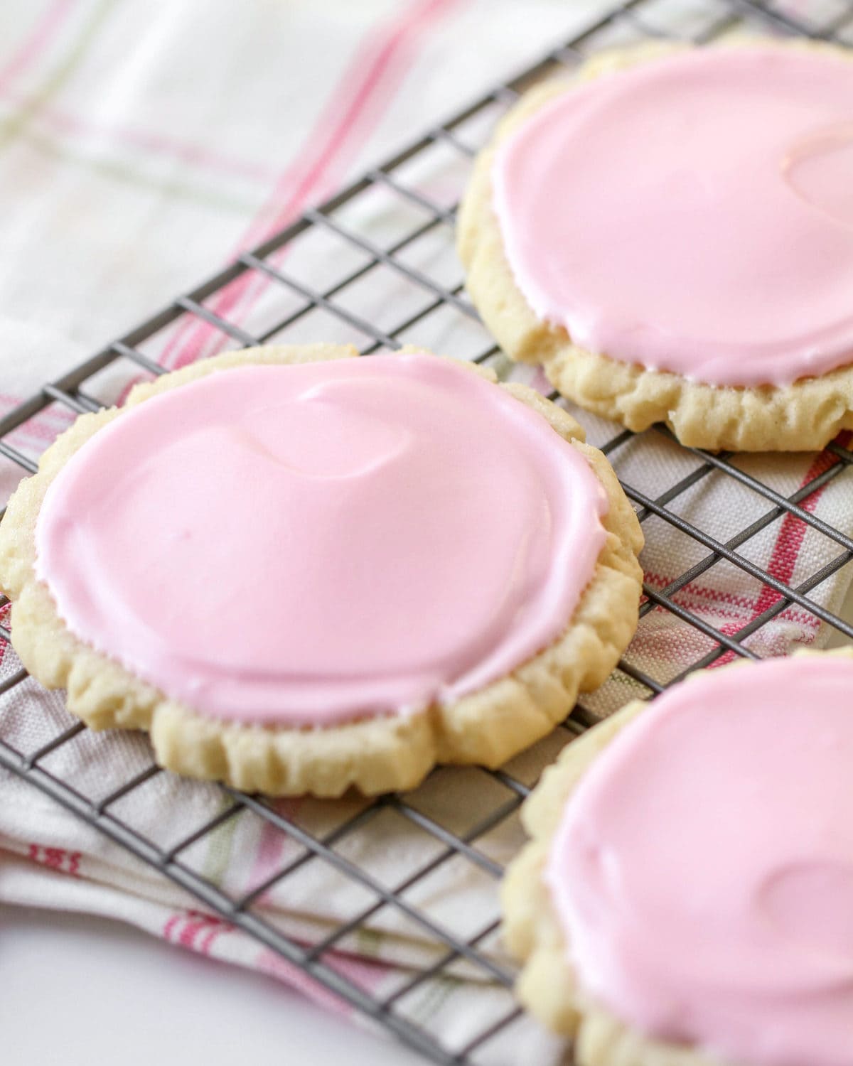 Swig sugar cookies with pink frosting on a wire rack