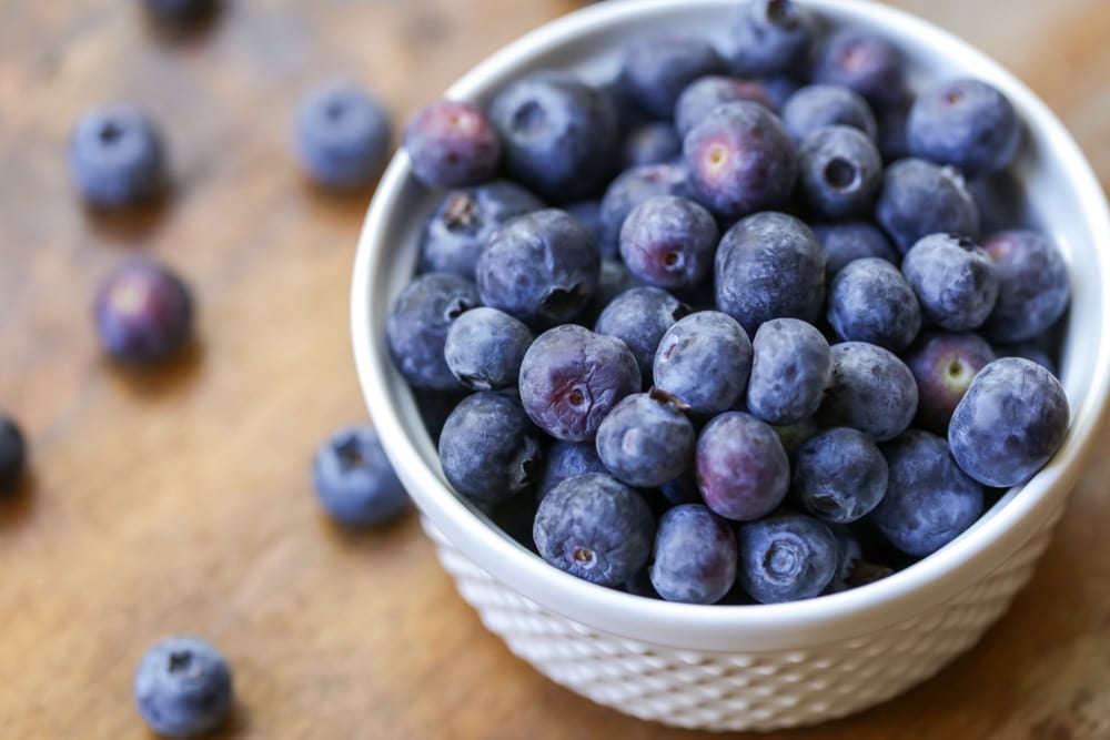 Small white bowl filled with fresh blueberries.