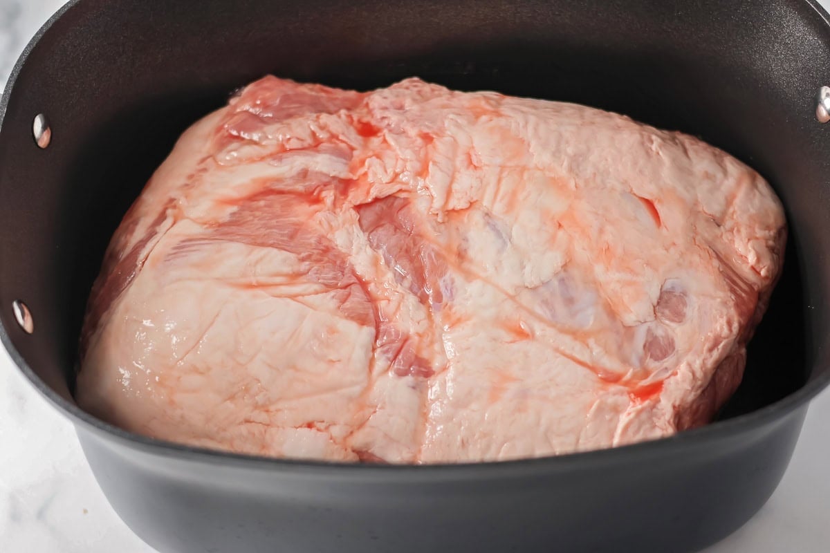 Pork butt in slow cooker to make homemade Kalua pork recipe.