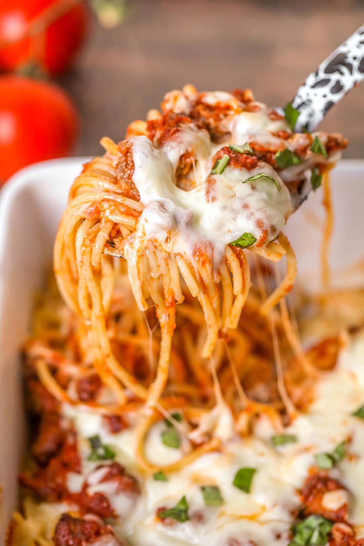 Close up of a spoonful of cheesy baked spaghetti.