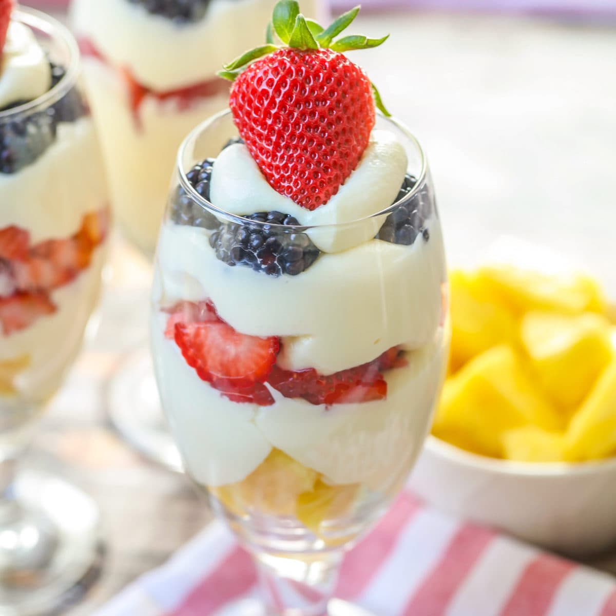 A dessert parfait layered and served in a glass and topped with a fresh strawberry.