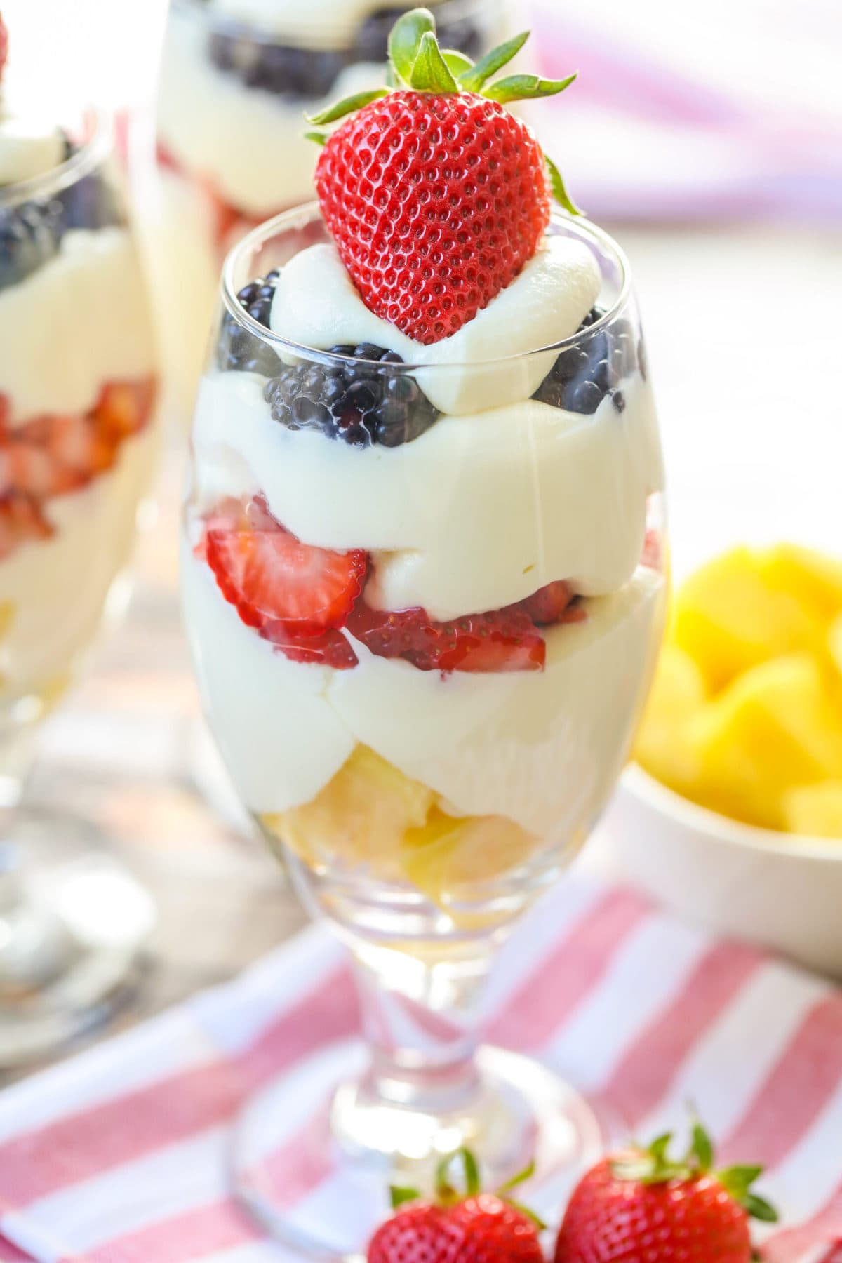 A dessert parfait layered in a glass and topped with a fresh strawberry.
