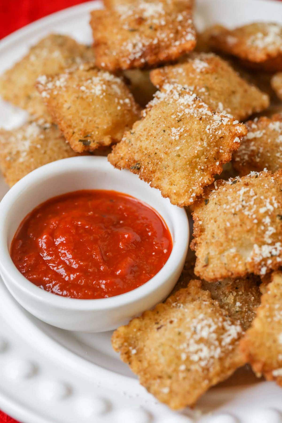 Fried ravioli served on a white plate with marinara.