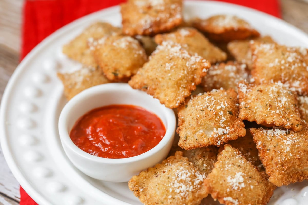 Fried ravioli served on a white plate with a side of marinara.