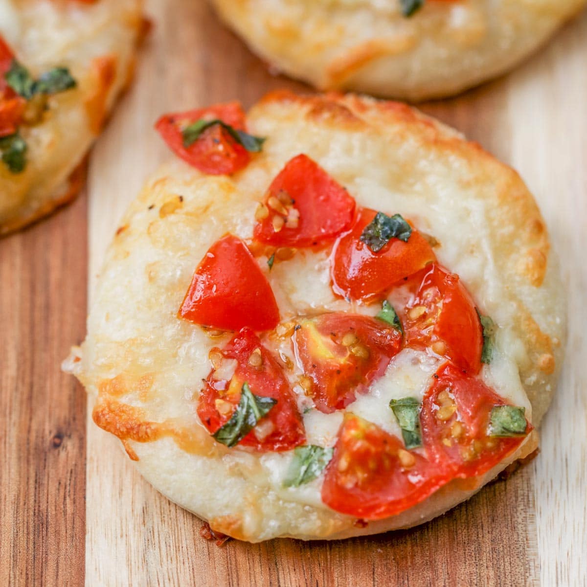 Close up of mini pizzas on a cutting board.