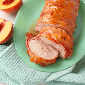 The perfect dinner solution for any night of the week! Pork tenderloin is wrapped in smokey slices of bacon and topped with a sweet peach preserve glaze. Sweet and savory flavors wrapped into one amazing meal!