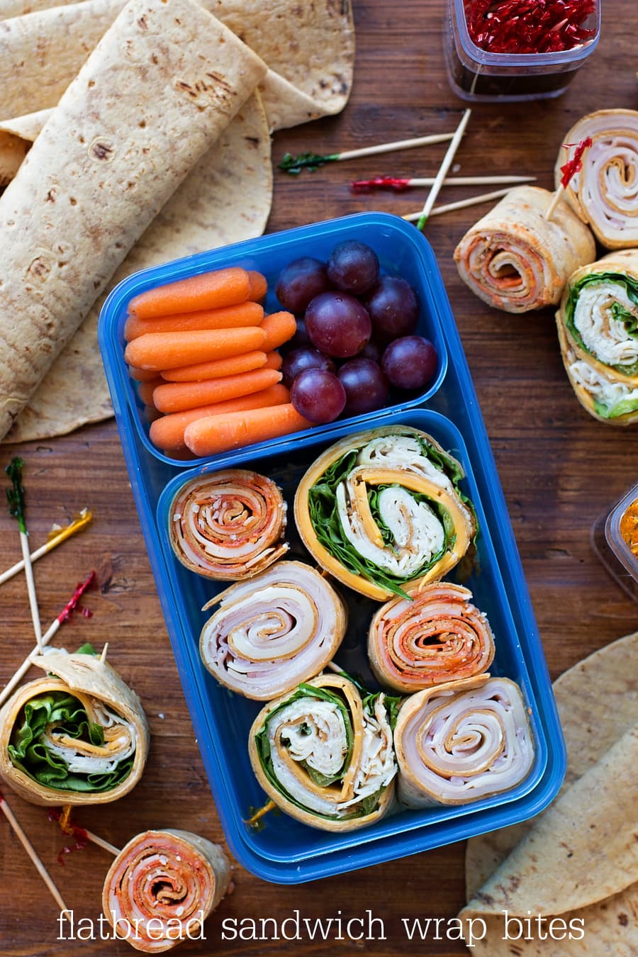 Flatbread Wrap Bites packed in a container with carrots and grapes.