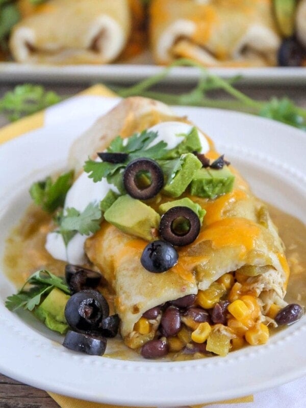 green chili smothered burrito with olives, cilantro and avocado on plate