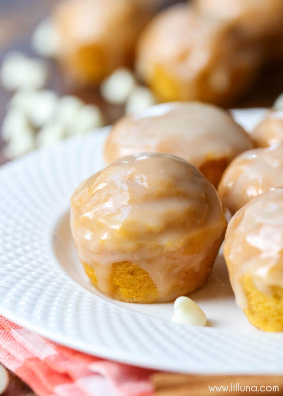 Thanksgiving desserts - mini glazed pumpkin donut muffins piled on a white plate.