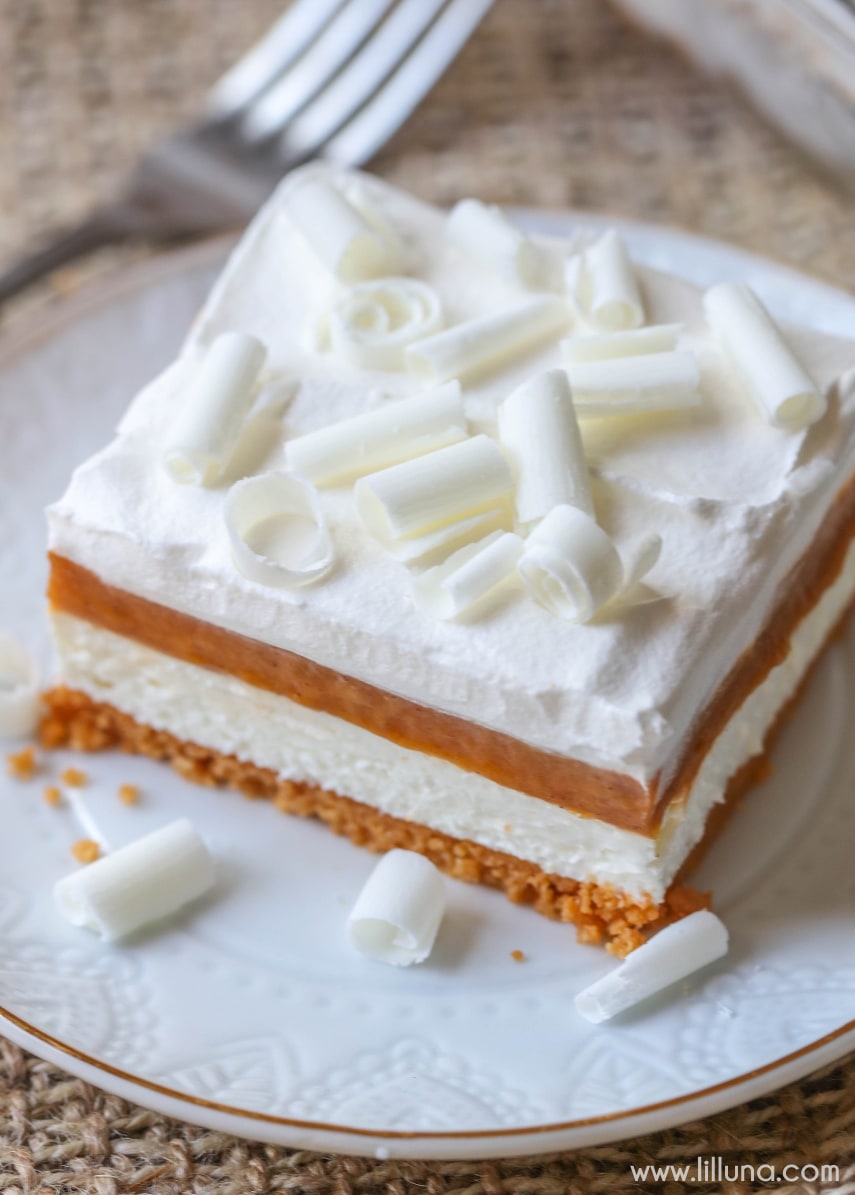 Pumpkin Lasagna - a delicious layered dessert with a Pumpkin Oreo crust, cream cheese layer, pumpkin pudding layer, and topped with cream and white chocolate curls. It's PHENOMENAL!