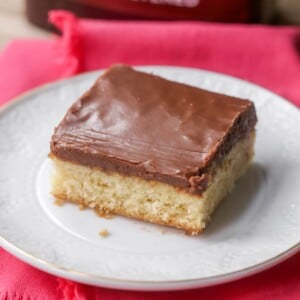 A slice of white sheet cake with chocolate frosting on a plate.