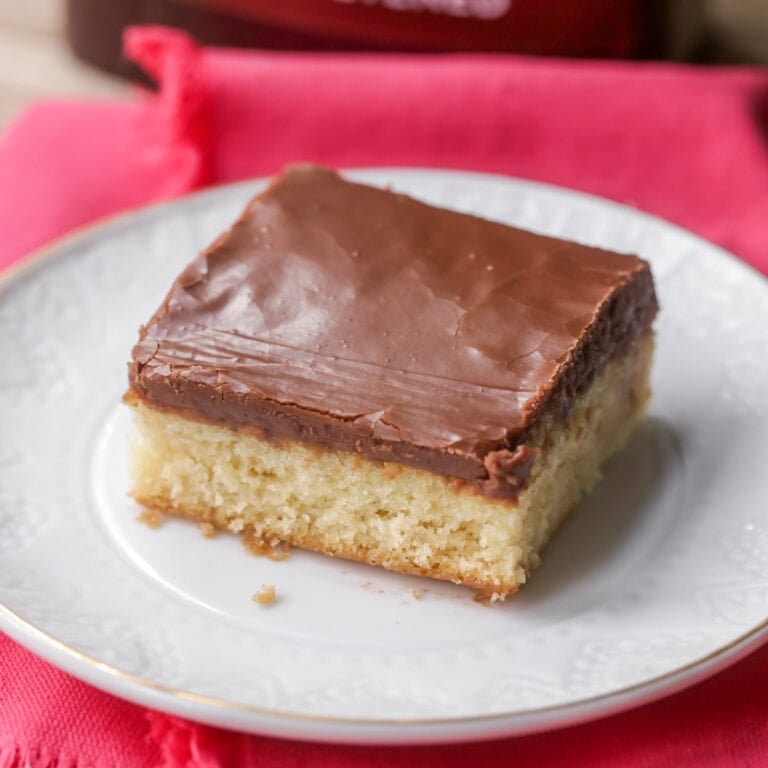 A slice of white sheet cake with chocolate frosting on a plate.