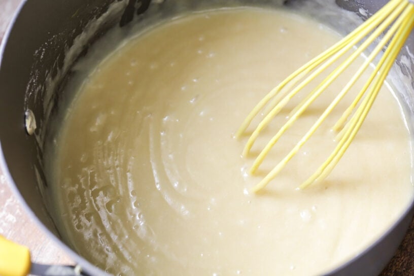 This White Sheet Cake with Chocolate Frosting is easy to make, melts in your mouth, and is always a crowd pleaser! Mixing white sheet cake batter in a pot.