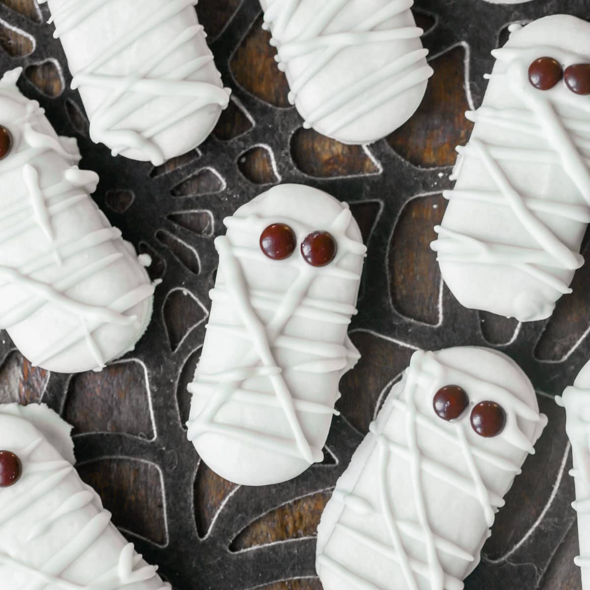 Halloween snacks - close up of mummy cookies topped with brown candy eyes.