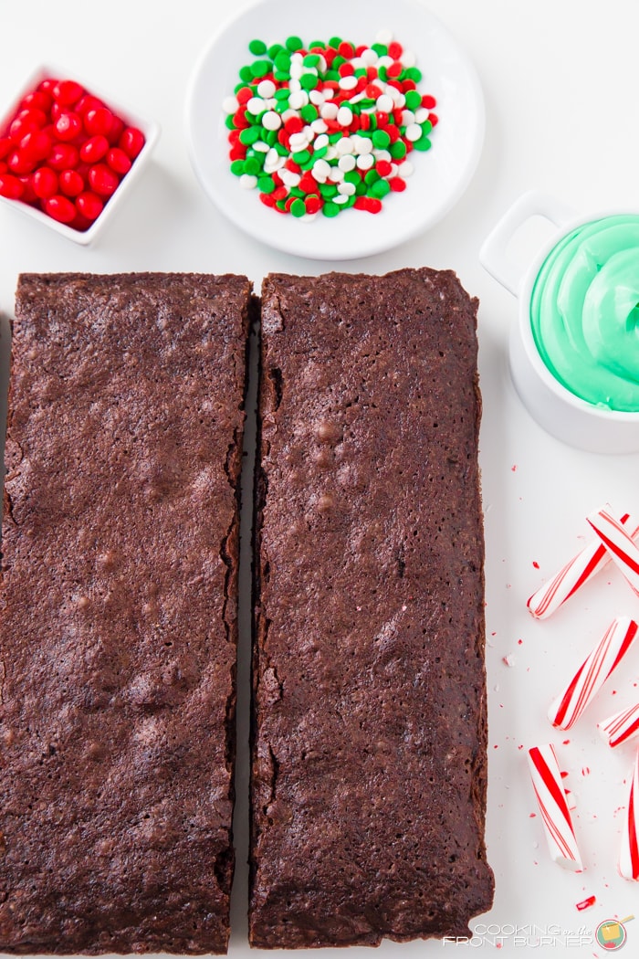 Cut brownies next to green frosting and candy for decorating.