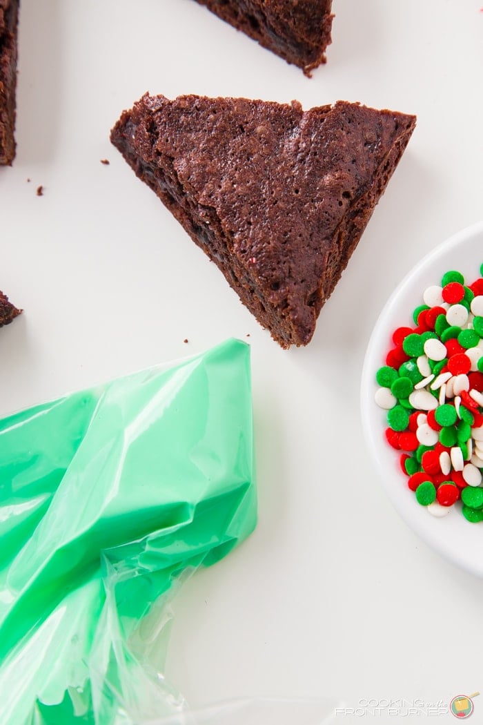 Triangle brownie with a bag of green frosting and Christmas sprinkles.