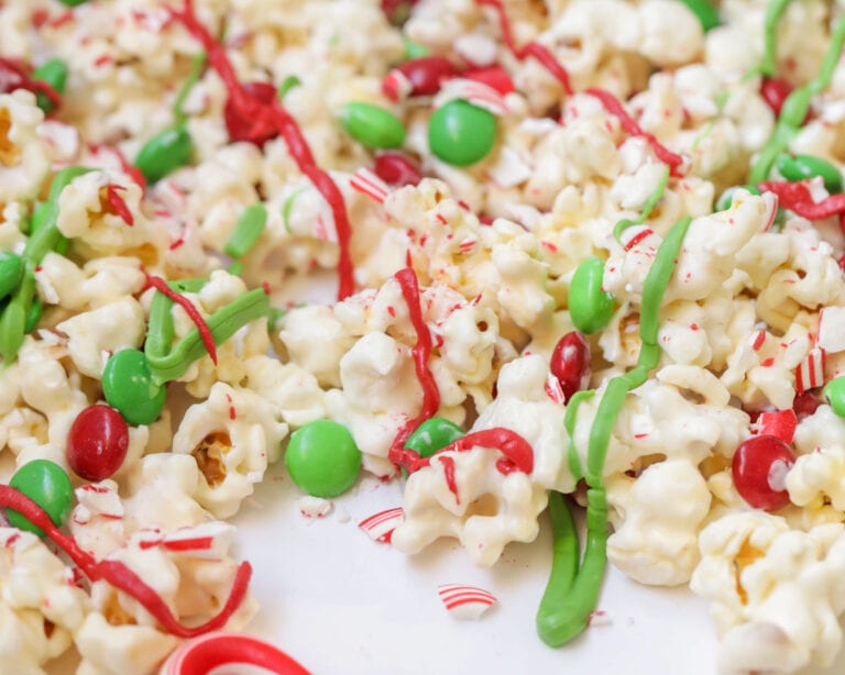 Christmas popcorn drizzled with chocolate and filled with M&Ms and crushed candy canes.