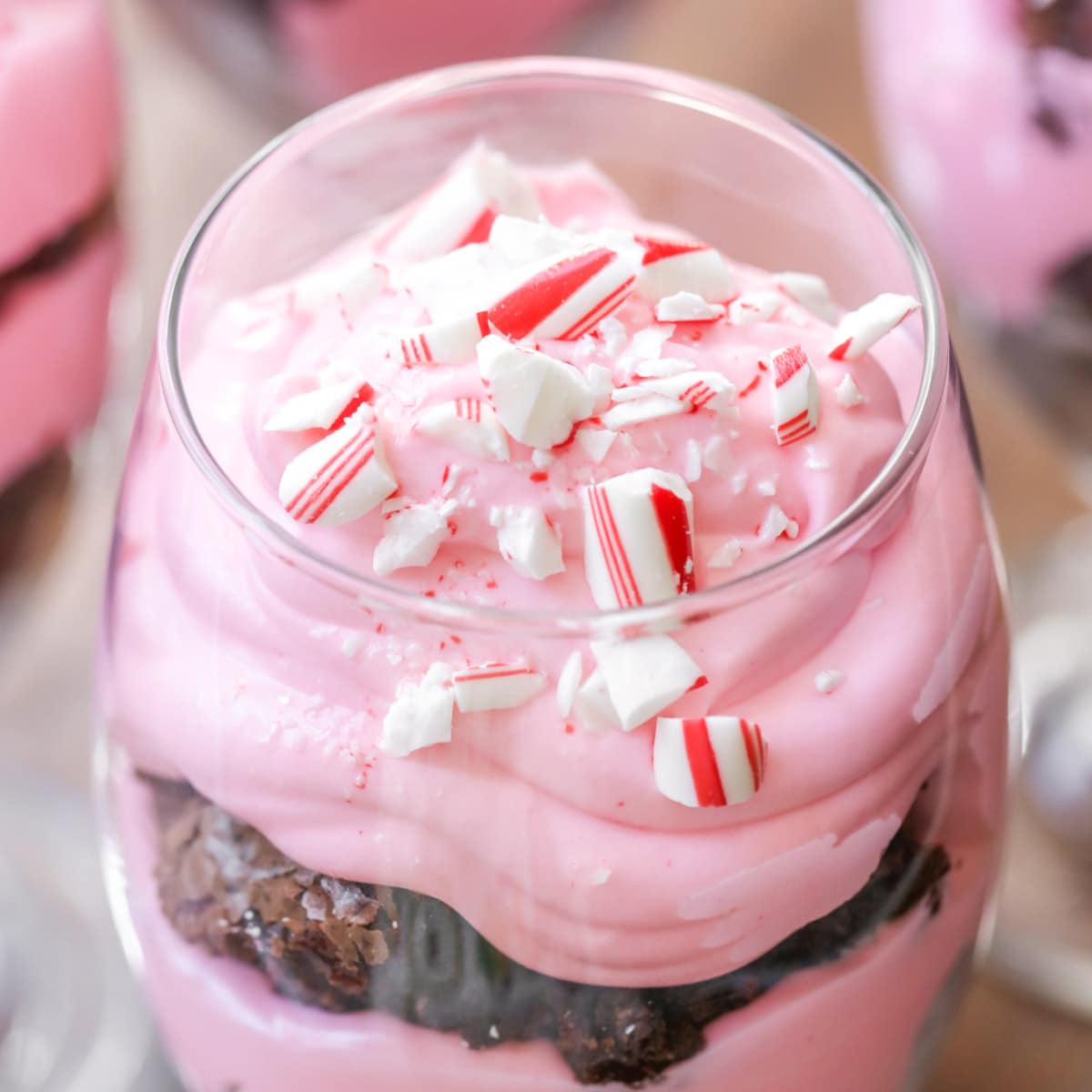 Peppermint brownie trifle layered in a glass goblet topped with crushed candy cane.