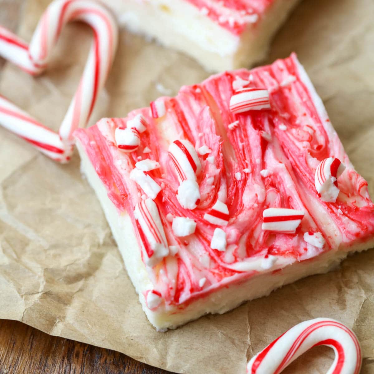 Creamy Peppermint Cheesecake Bars cut and served on brown paper with candy cane hearts.