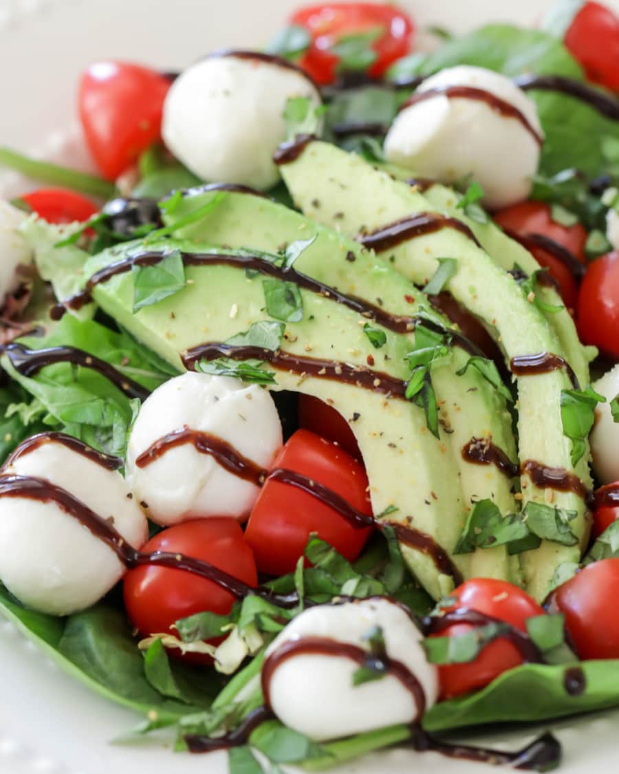 lettuce topped with avocado, tomato and mozzarella drizzled in balsamic