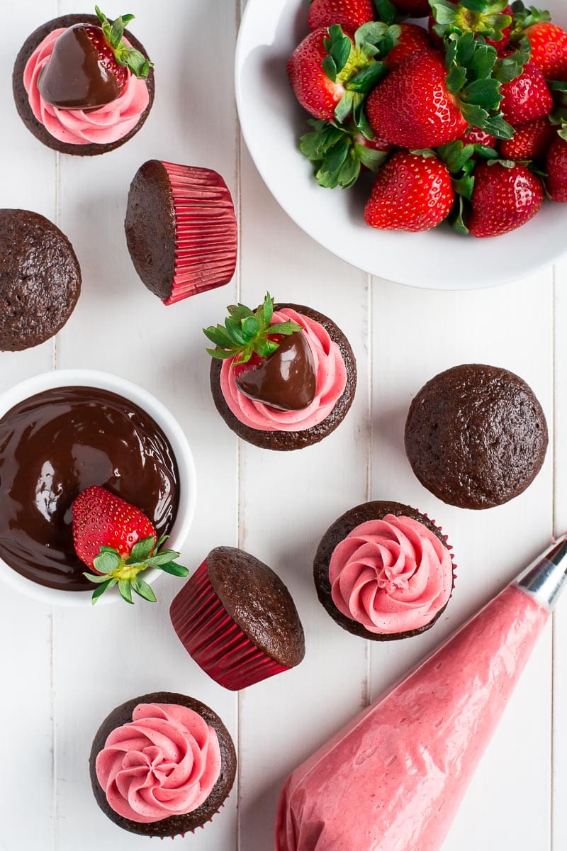 Chocolate Covered Strawberry Cupcakes with a bowl of strawberries and a frosting bag