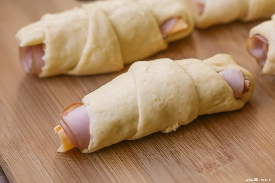 assembling unbaked Hot Ham and Cheese on a wooden cutting board