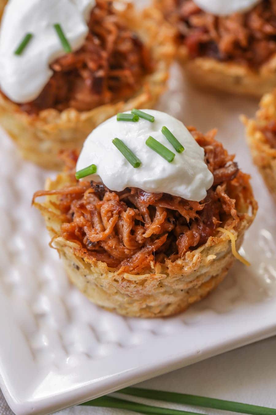 Christmas appetizers -  close up of loaded pulled pork cups topped with sour cream and chives.