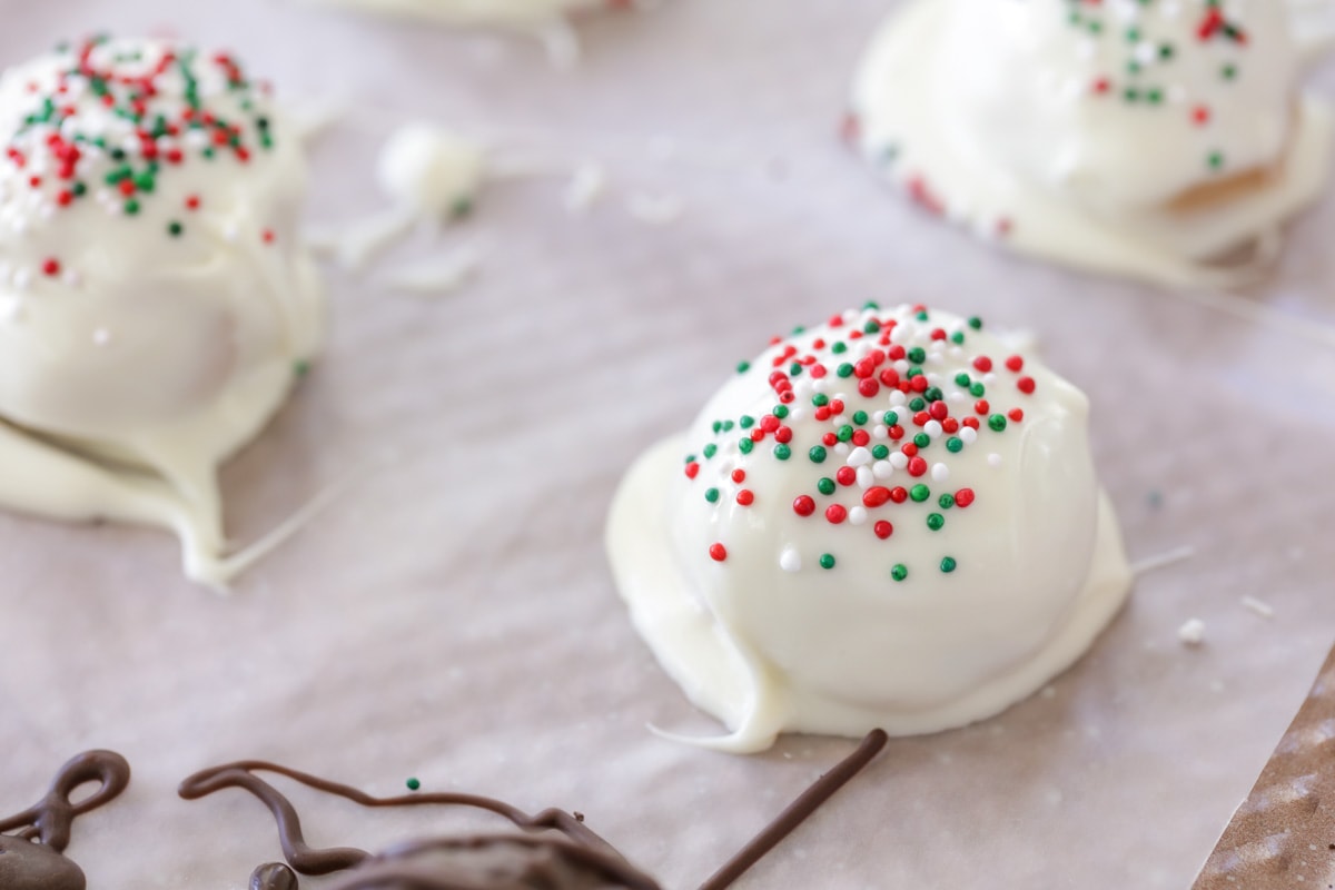 candy coated peanut butter snowballs topped with sprinkles on wax paper
