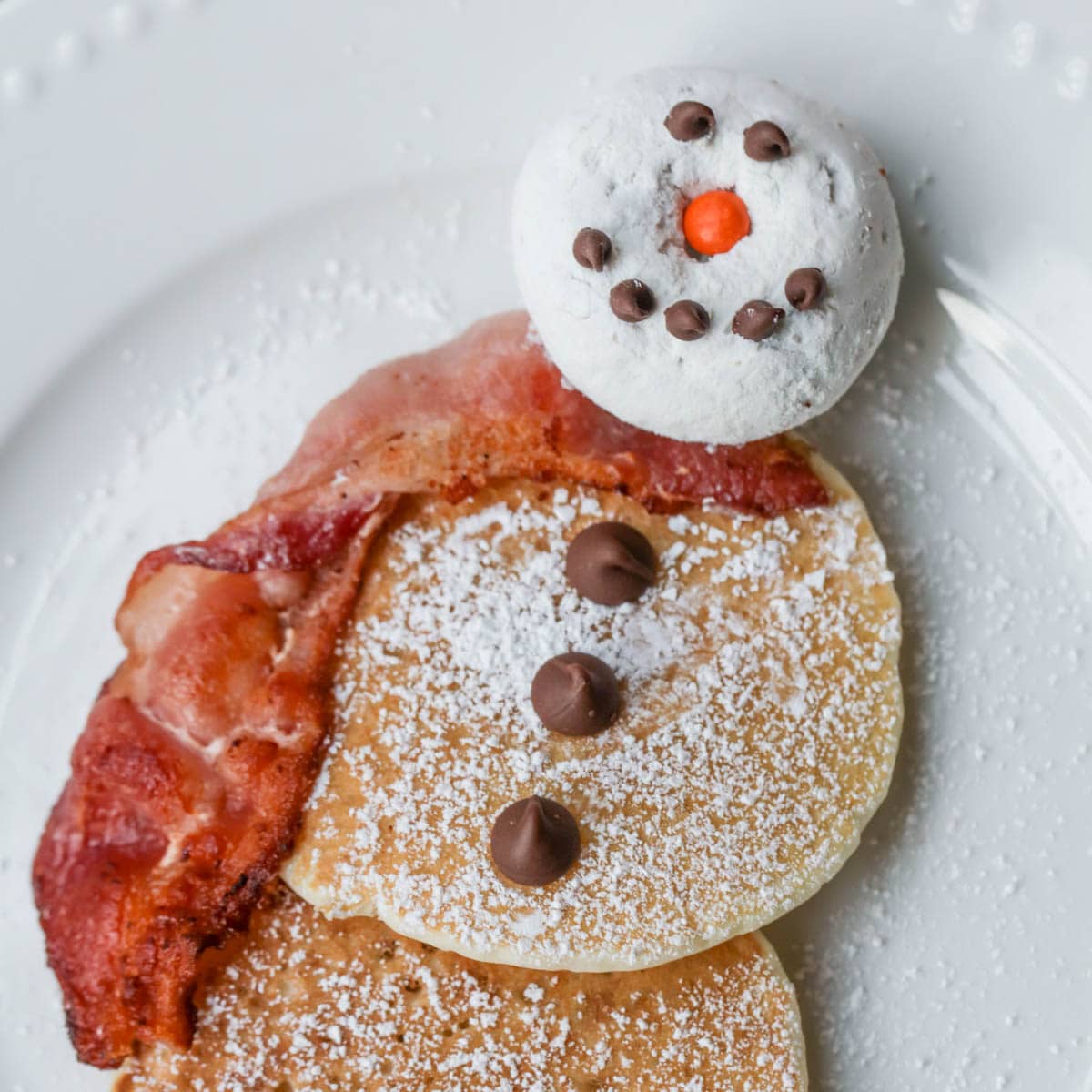 Christmas snowman pancakes plated and decorated with chocolate chips.