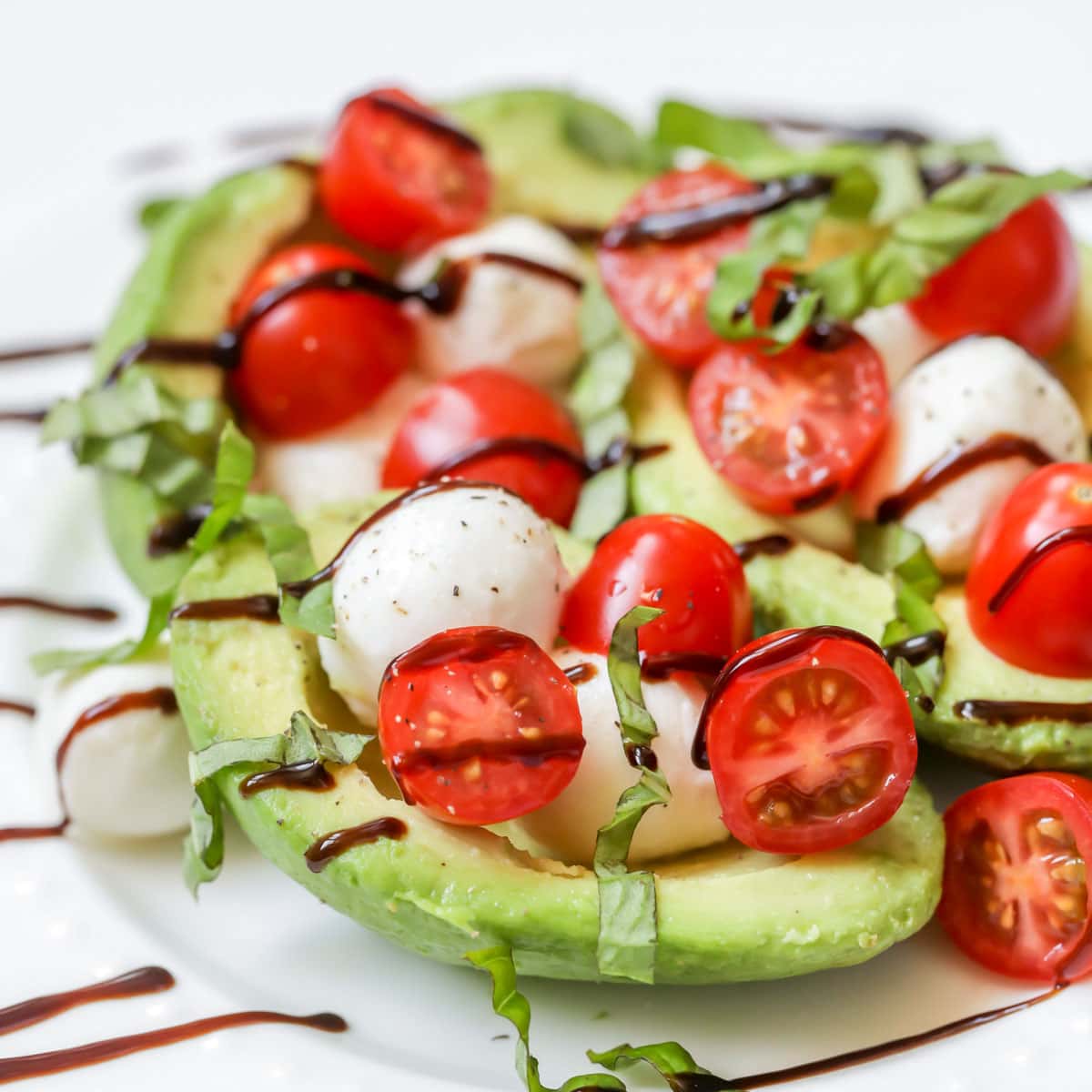 Caprese Avocados topped with tomatoes, mozzarella, basil, and balsamic