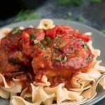 Chicken cacciatore on grey plate served over pasta